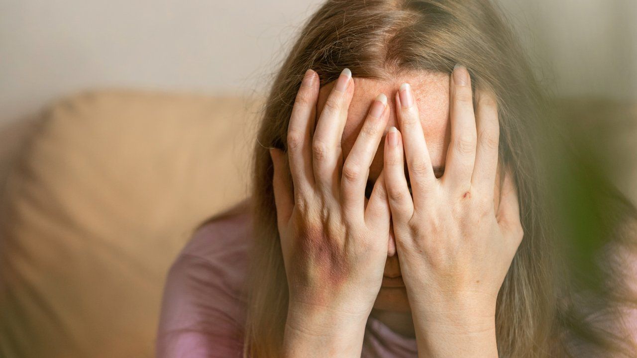 Woman with her hands over her face crying.