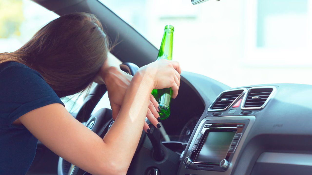 Woman passed out at the wheel with beer bottle in hand.