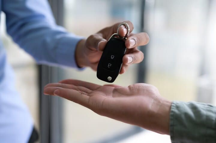 Person handing over car keys to someone else.