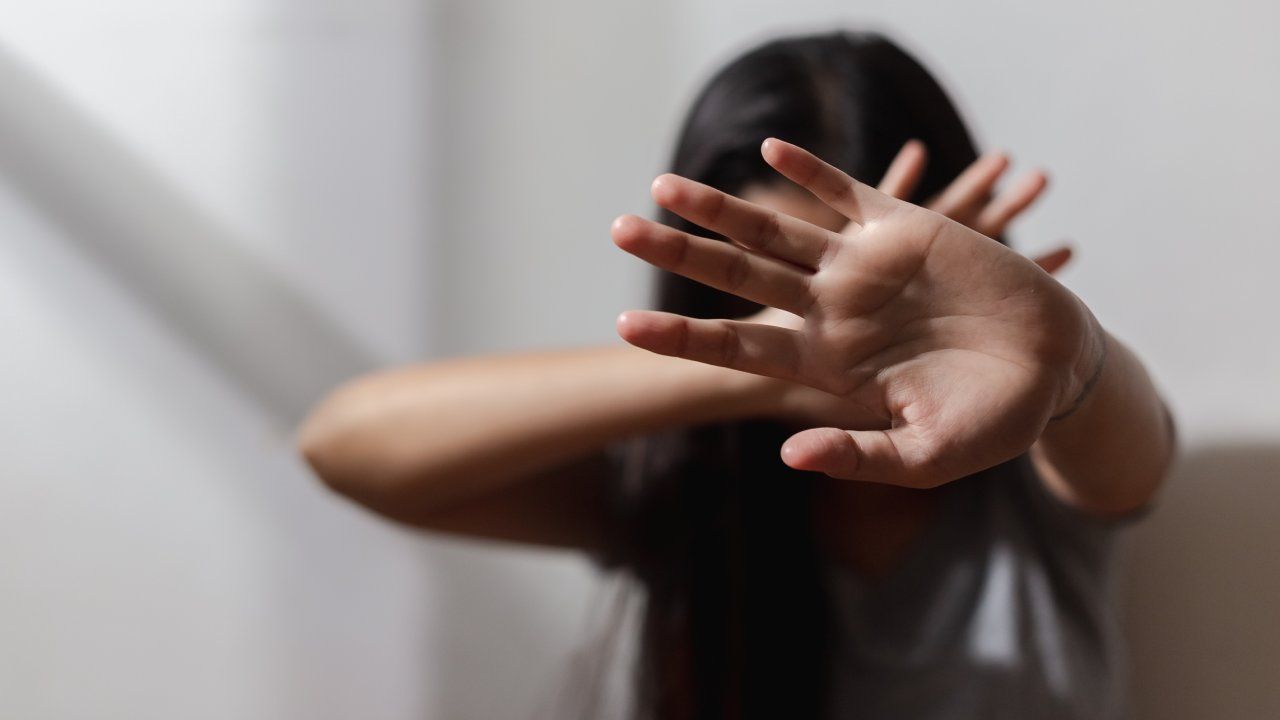 Woman with hands crossed in front of her face.