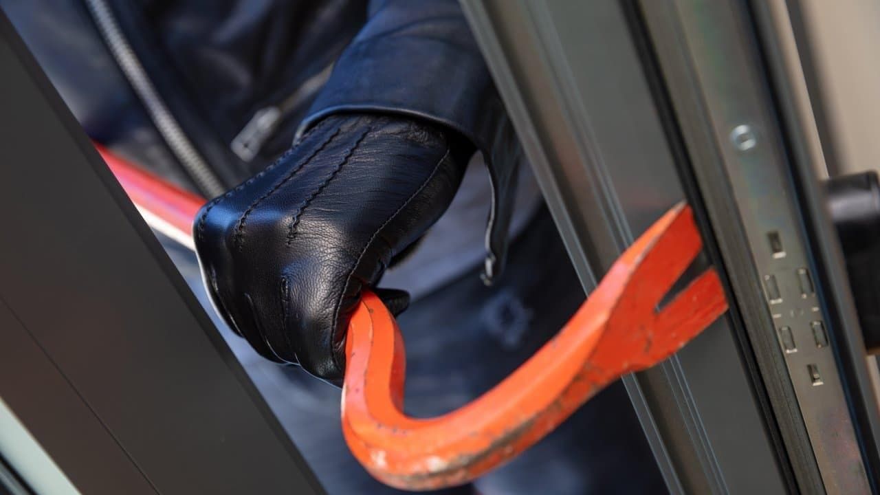 Burglar holding crowbar in front of a door.