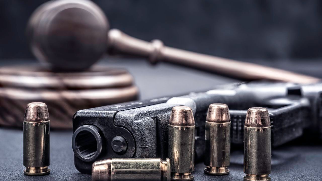 Gavel next to a gun and ammo on a table.