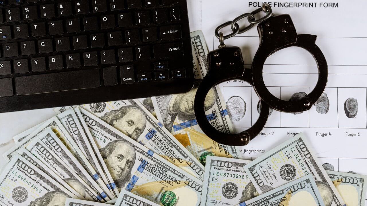 Laptop and handcuffs with hundred dollar bills.